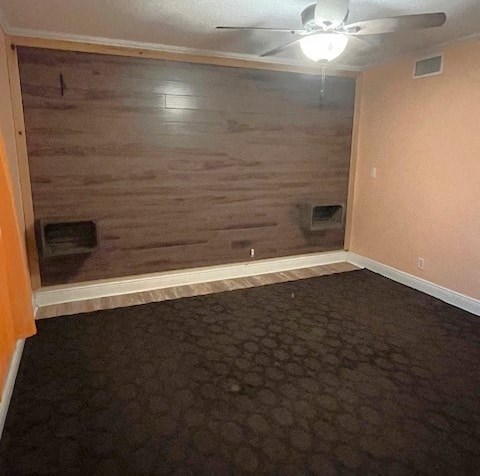 a empty room with a wooden wall and a ceiling fan