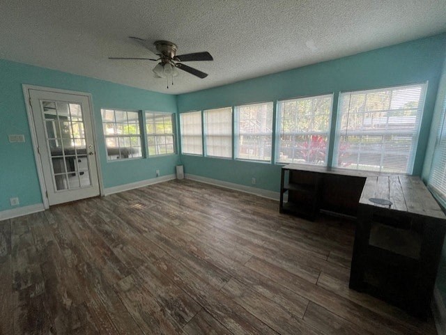 an empty living room with a ceiling fan and windows