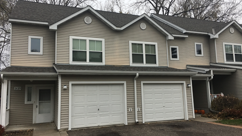 a tan house with two garage doors