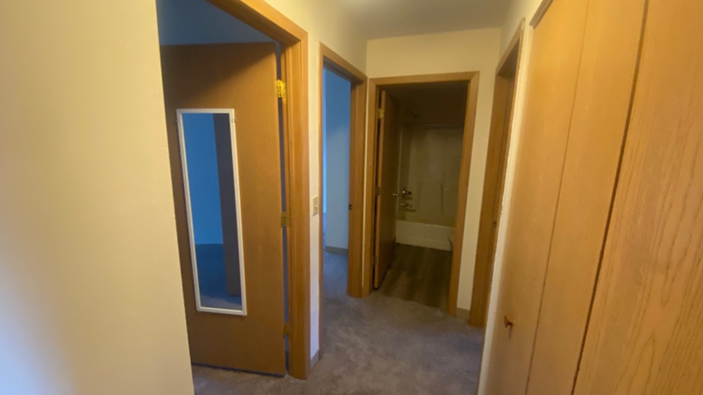 a hallway with two doors and a door to a bathroom