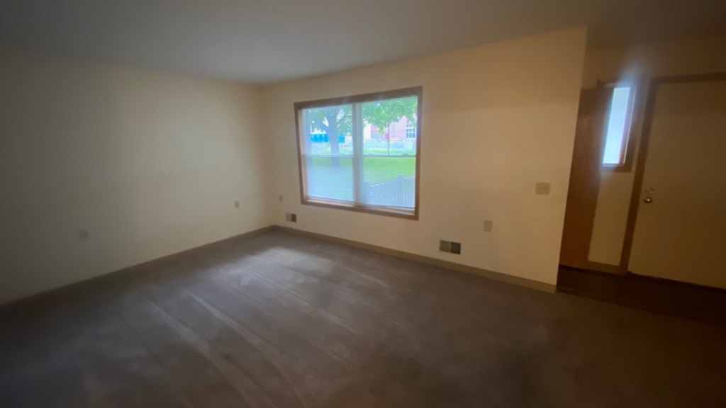 an empty living room with a large window and wooden floors