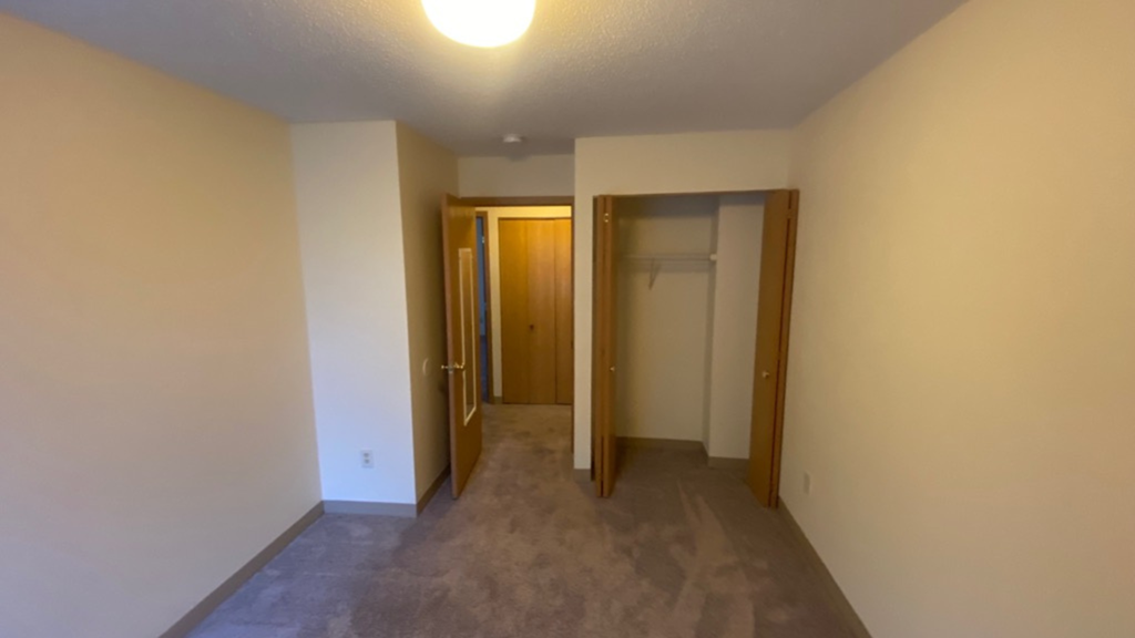 an empty living room with a hallway to a closet and a door to a bathroom