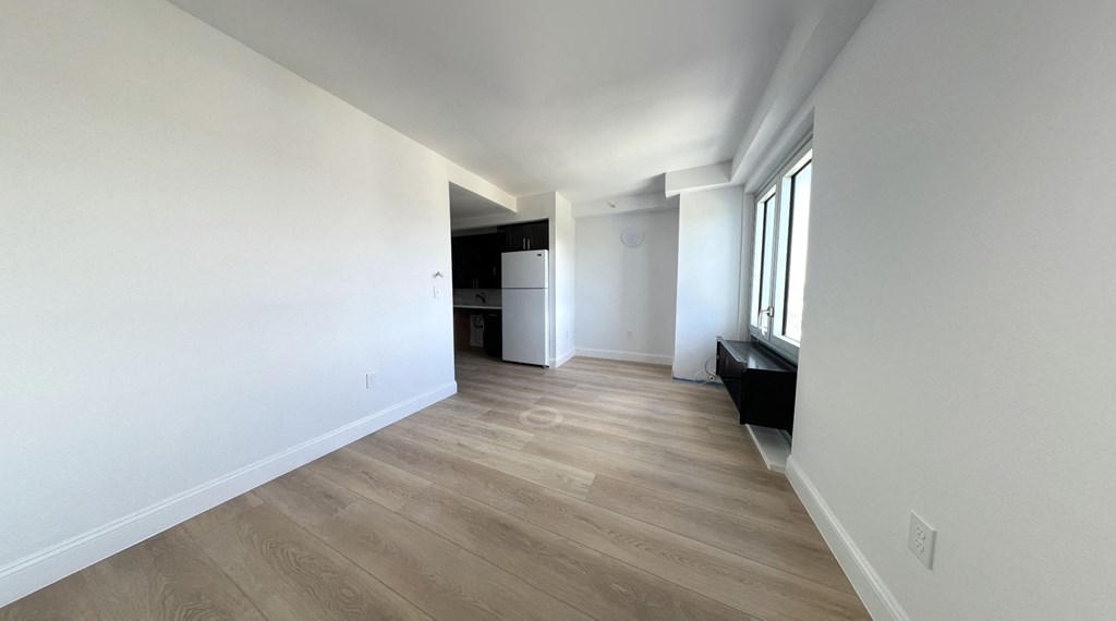 a renovated living room and kitchen with white walls and wood flooring