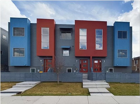 a blue and red house with a sidewalk in front of it