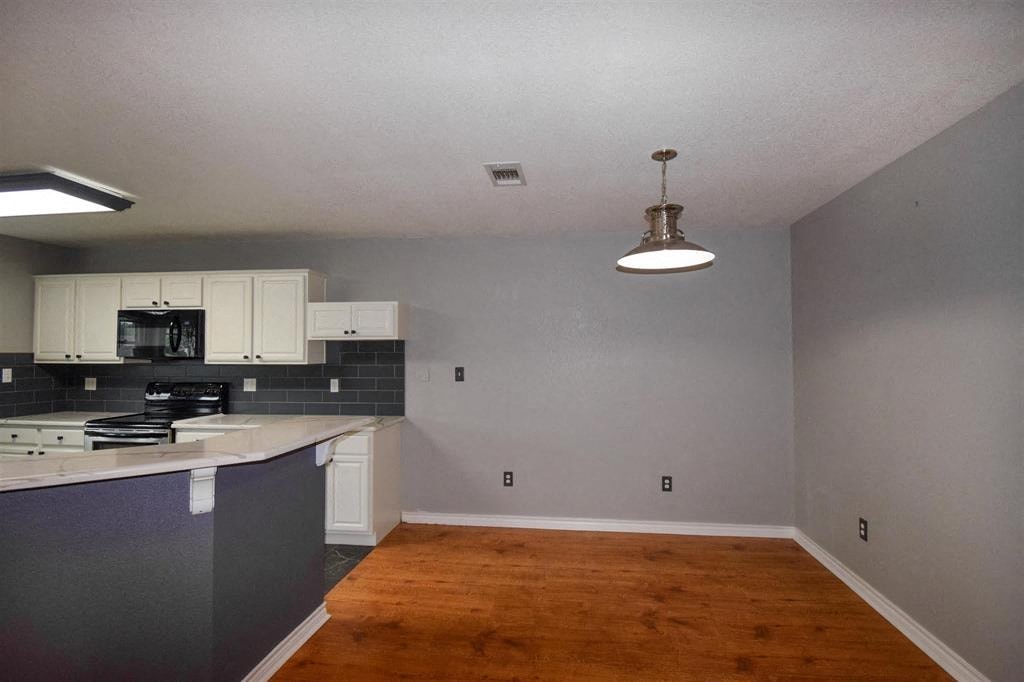 an empty living room with a kitchen and a light