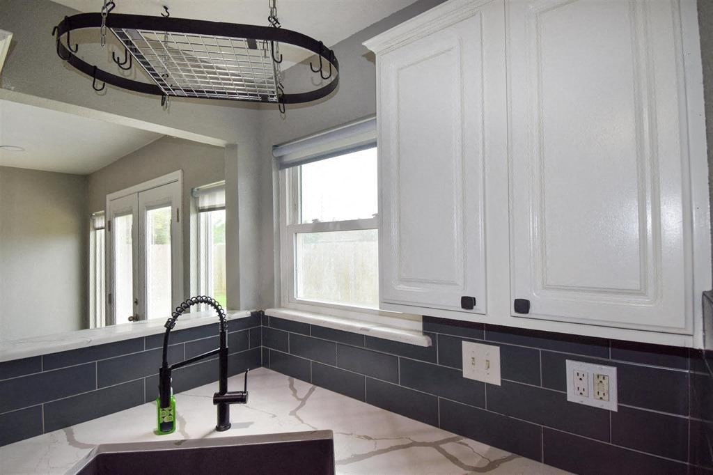 a kitchen with white cabinets and a sink and a window