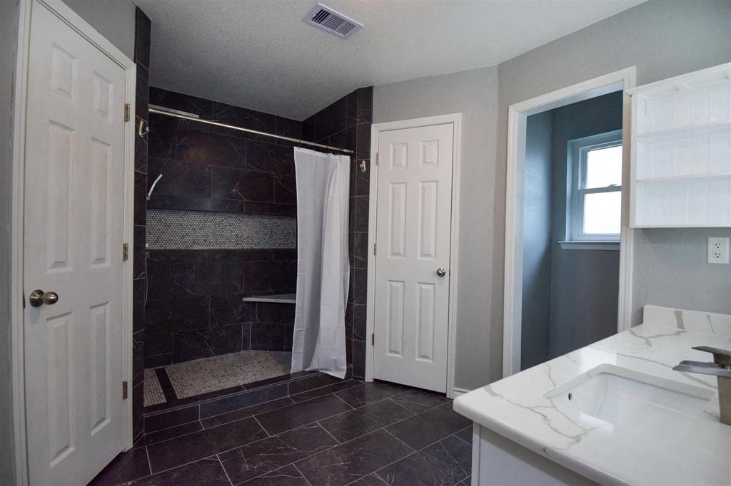a bathroom with a shower and a sink and a door