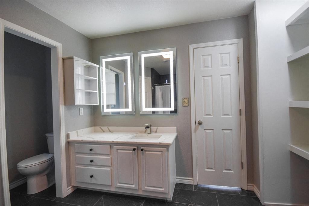 a bathroom with a sink toilet and two mirrors