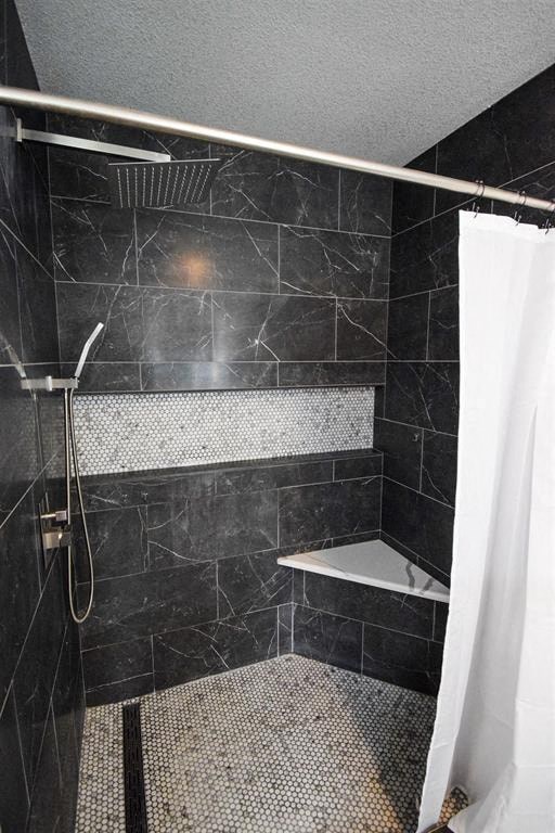 a black tiled bathroom with a shower and a white shower curtain