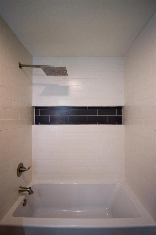 a white bath tub in a white tiled bathroom
