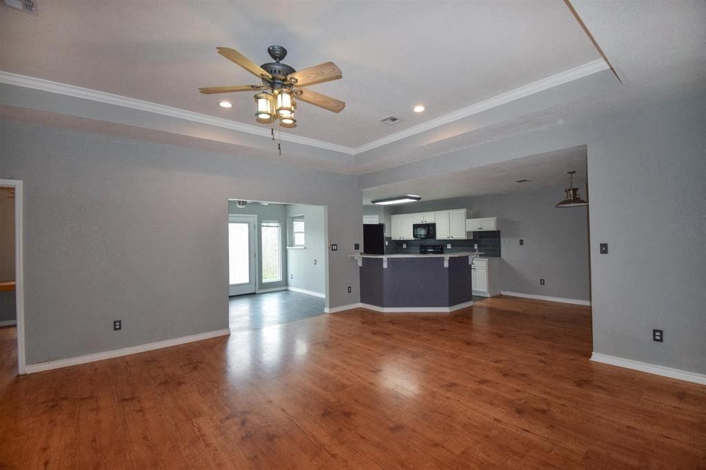 an empty living room and kitchen with a ceiling fan