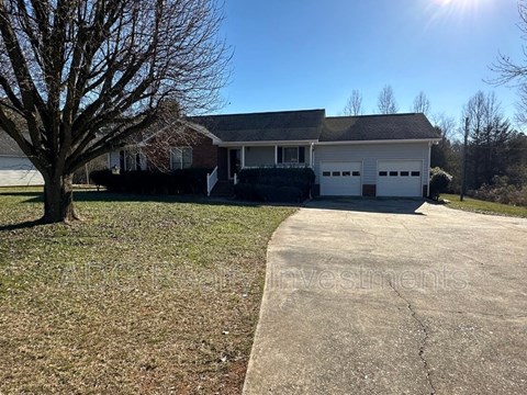 A house with a driveway and a tree in front of it.