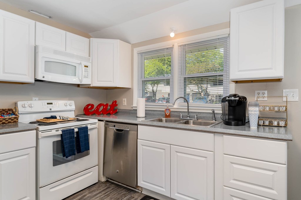 a kitchen with white cabinets and a sink and a dishwasher