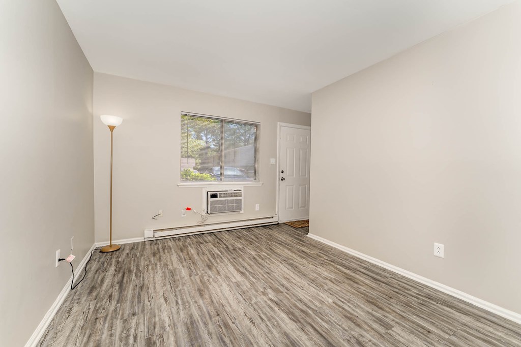 a living room with white walls and wood flooring and a window