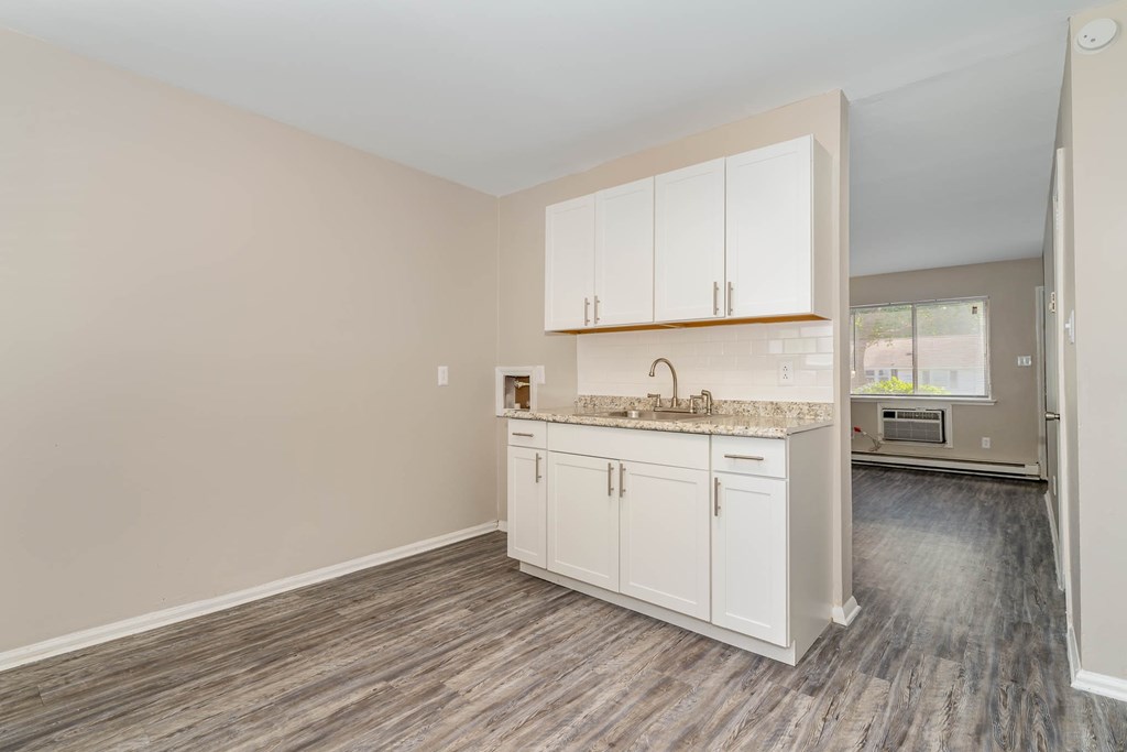 an empty kitchen with white cabinets and a counter top