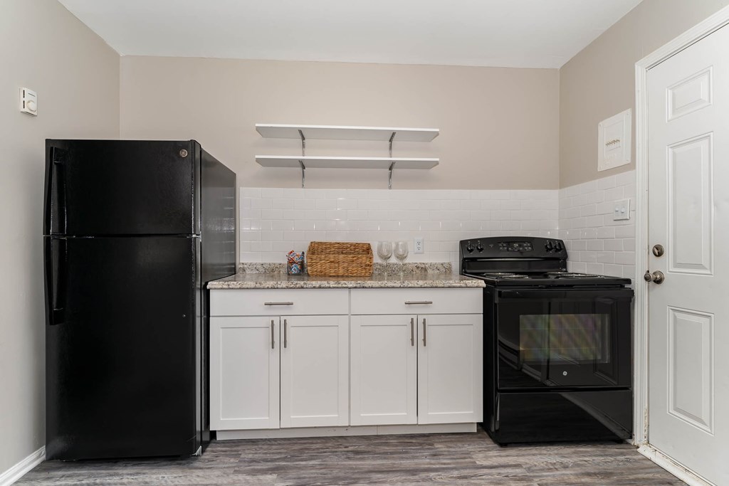 a kitchen with black appliances and white cabinets and a black refrigerator