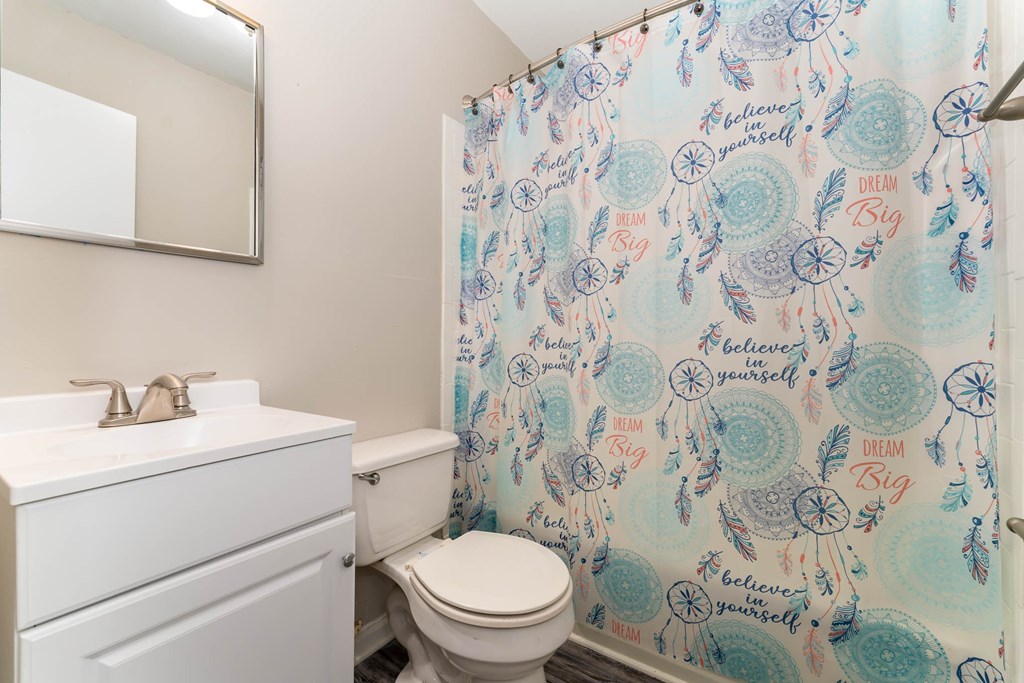 a bathroom with a shower curtain and a sink and a toilet