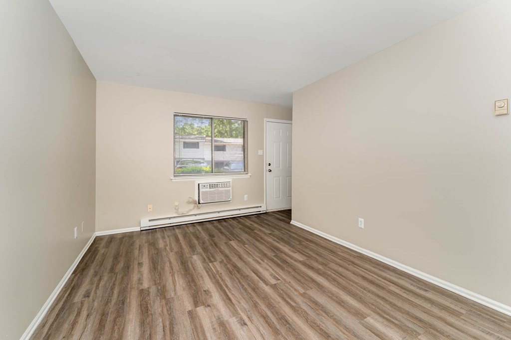 an empty living room with wood flooring and a window