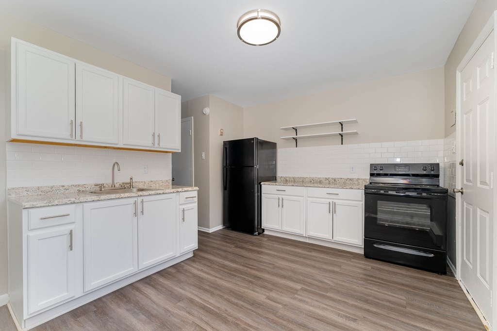 a kitchen with white cabinets and a black stove and refrigerator