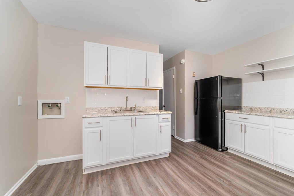 a kitchen with white cabinets and a black refrigerator