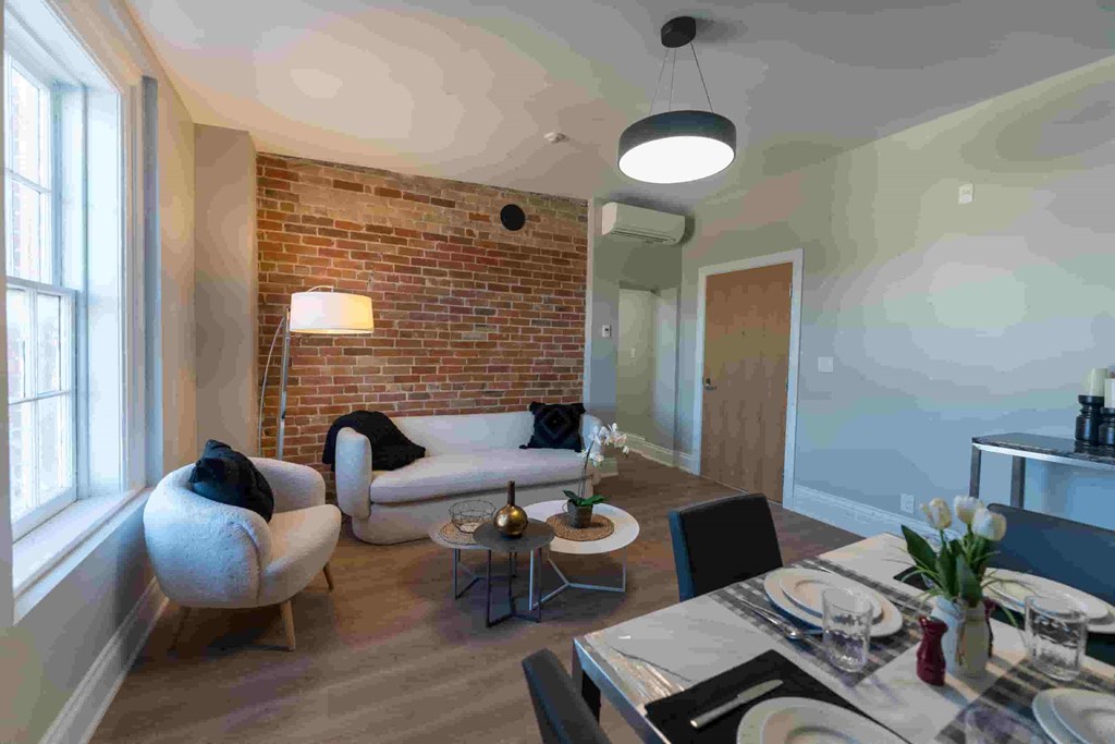 a living room and dining room with a table and chairs and a brick wall