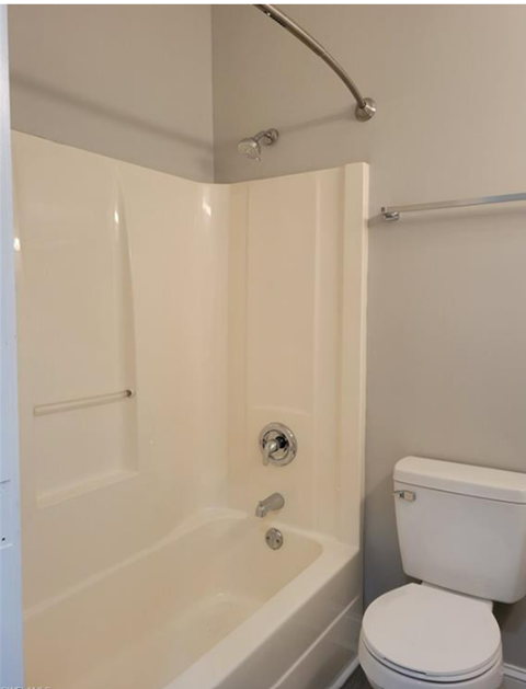 A white toilet sits next to a white bathtub in a bathroom.