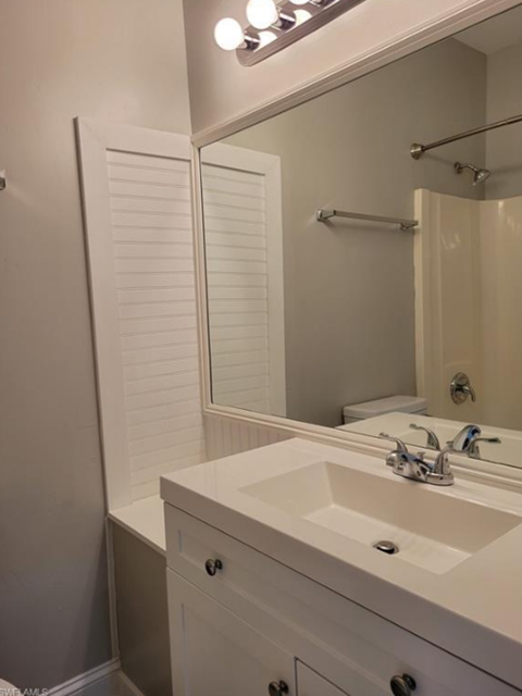 A white bathroom with a sink and mirror.