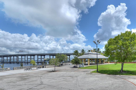 A park with a gazebo, benches, and a bridge in the background.