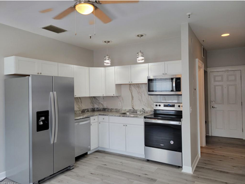 A modern kitchen with a stainless steel refrigerator and white cabinets.