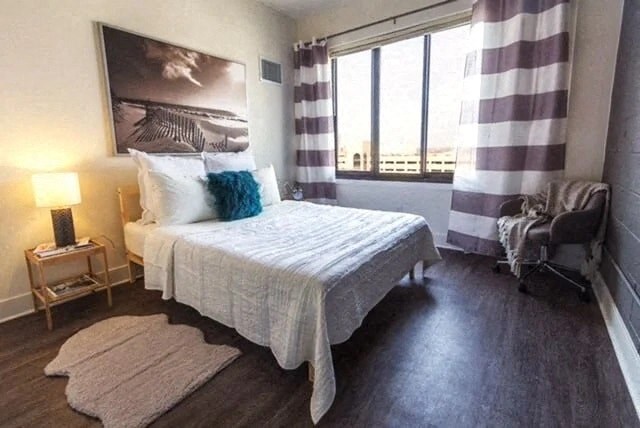 a bedroom with a bed and a window with striped curtains