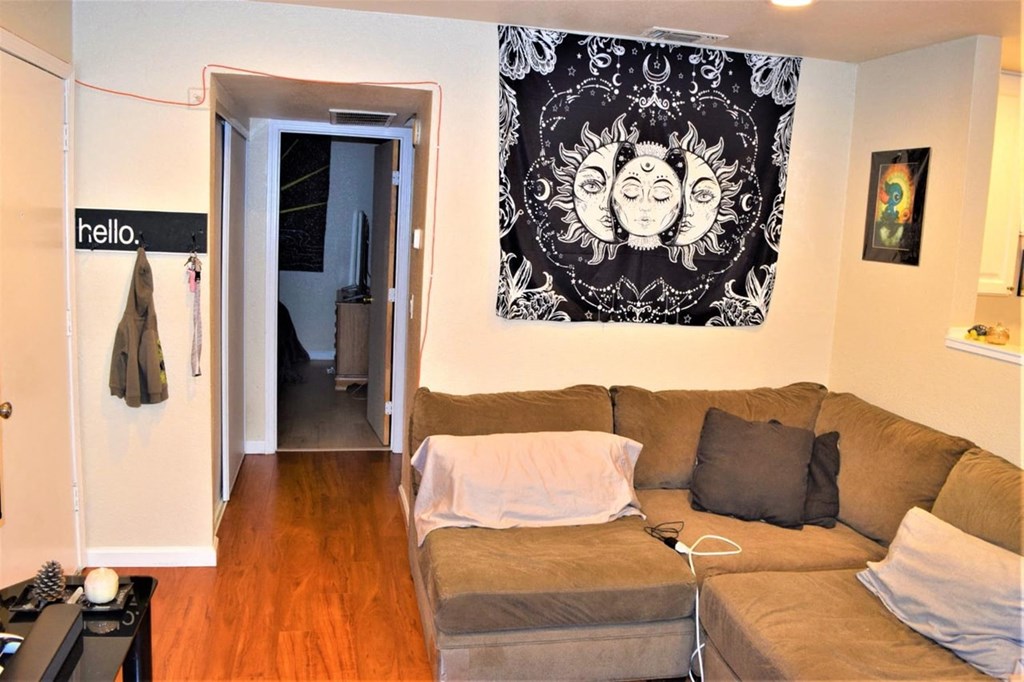 A living room with a couch and a door with a sign that says "hello.".