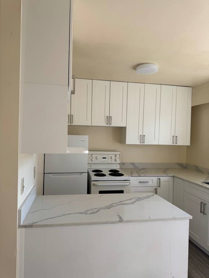 A kitchen with white cabinets and a white stove top oven.