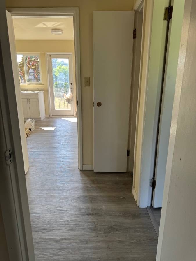 A hallway with a white door and a grey floor.