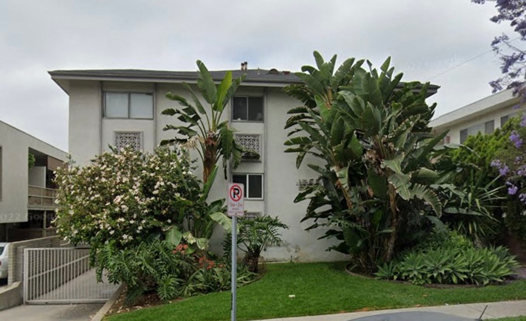 a white building with palm trees and a no parking sign