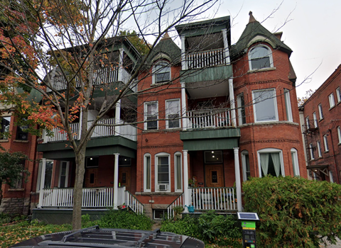 A large red brick house with a green trim.