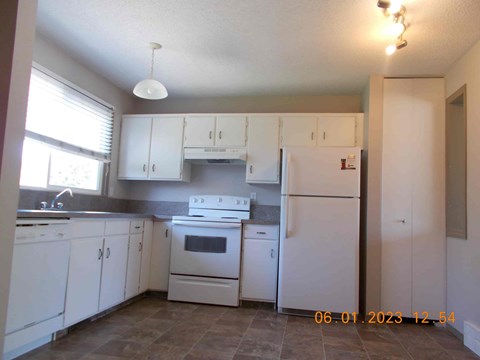 a kitchen with white cabinets and appliances and a window