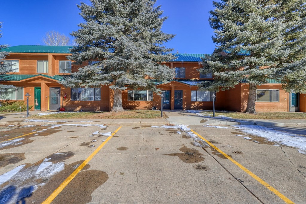 an empty parking lot in front of a building with trees
