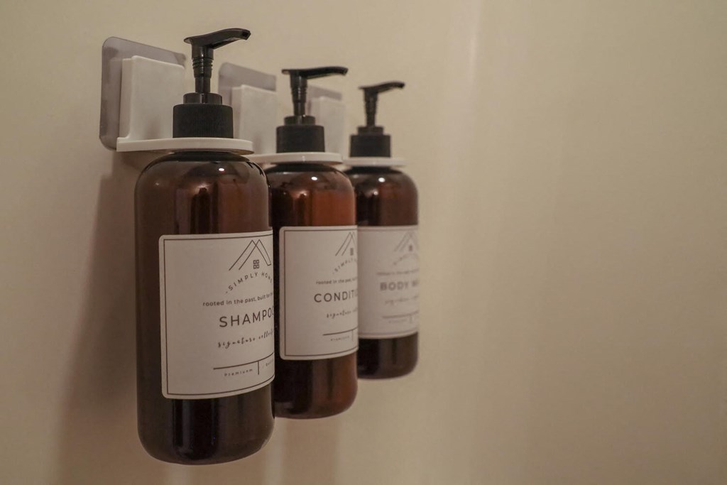 three bottles of shampoo and lotion hanging on a wall