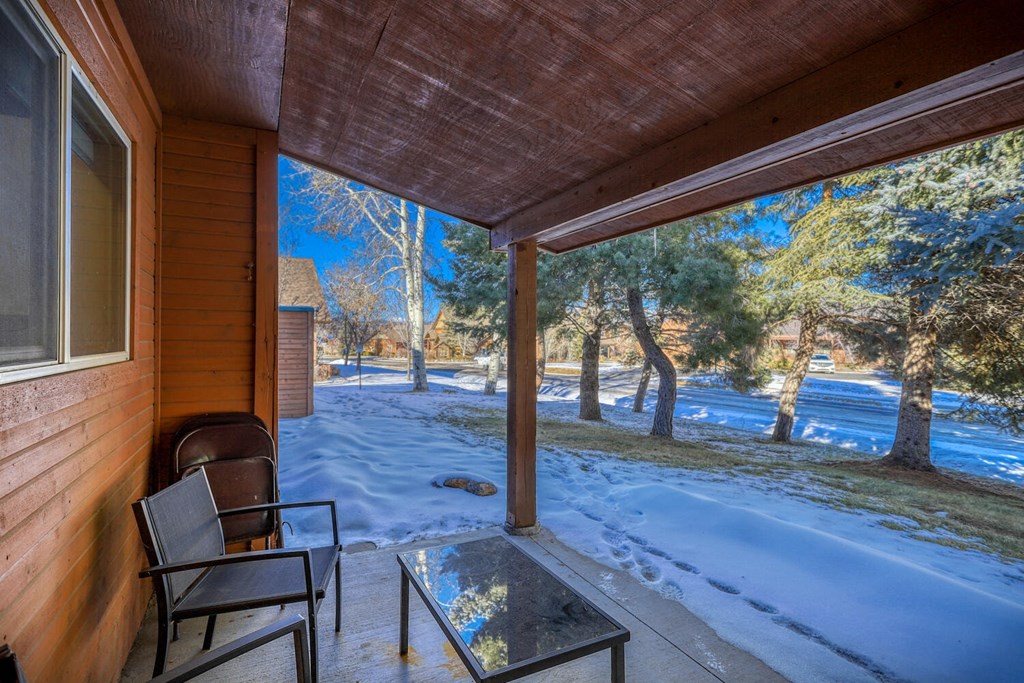 a patio with two chairs and a glass table overlooking the snow