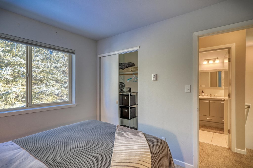 a bedroom with a large window and a door to a bathroom