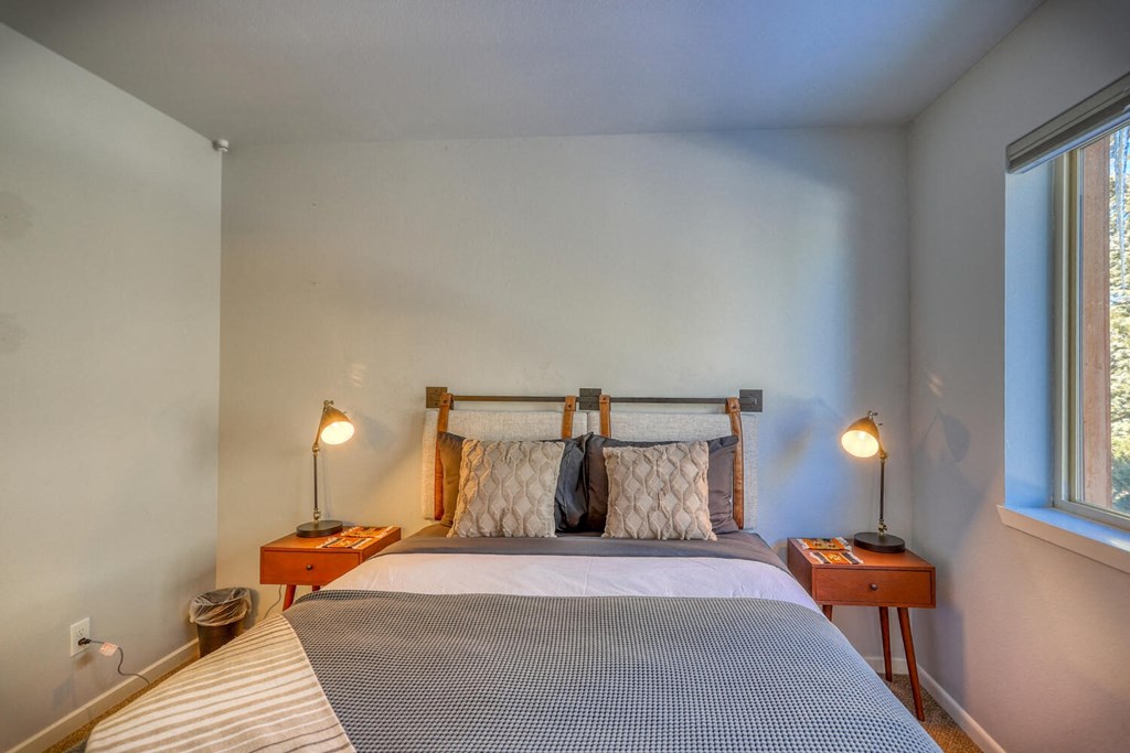 a bedroom with a bed and two lamps and a window