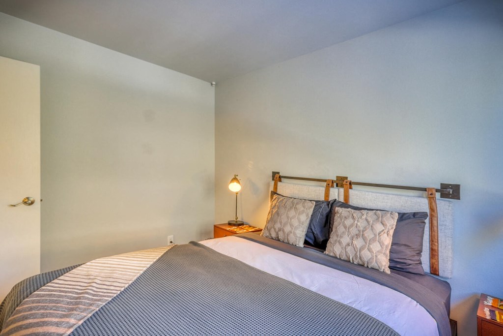 a bedroom with a bed and a nightstand with a lamp