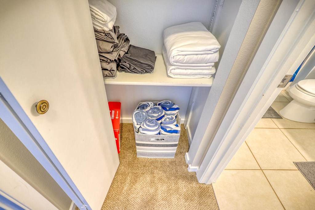 a bathroom with a closet with towels and a toilet