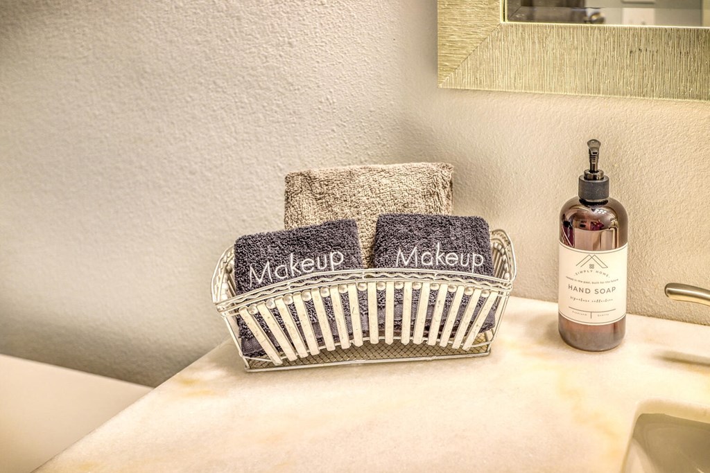 a bathroom with a basket with two towels and a bottle of soap