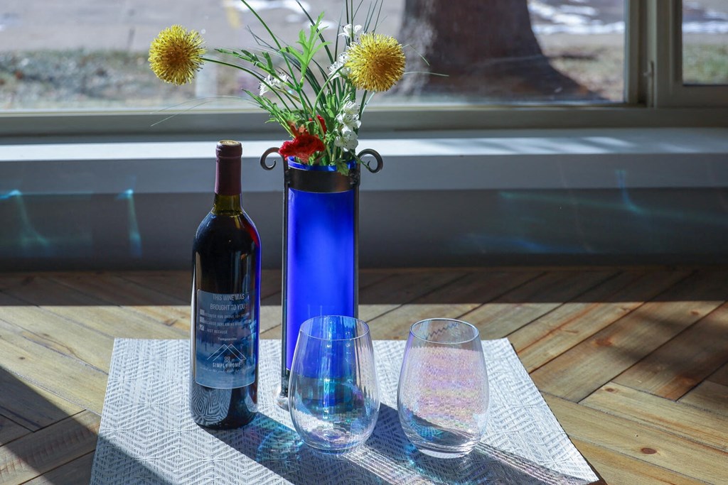 a table with two wine glasses and a blue vase with flowers