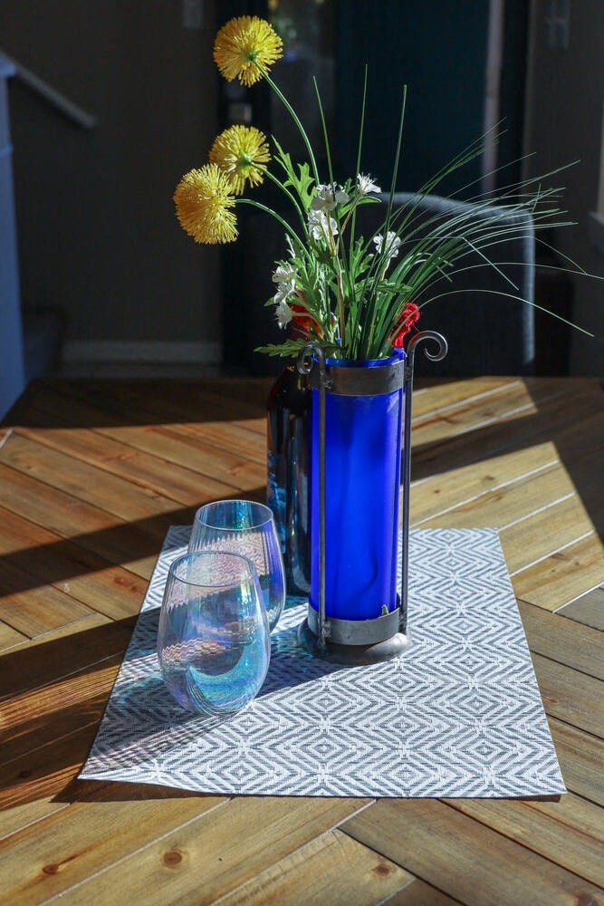 a table with a blue vase with flowers and two wine glasses