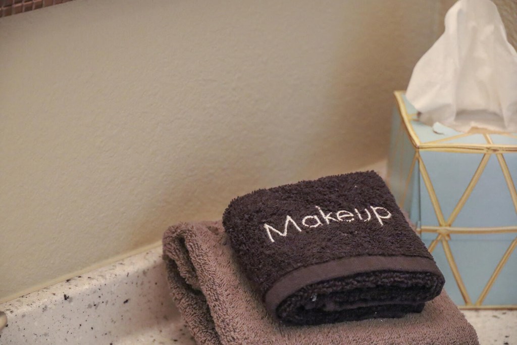 a stack of towels on a bathroom counter with a make up towel