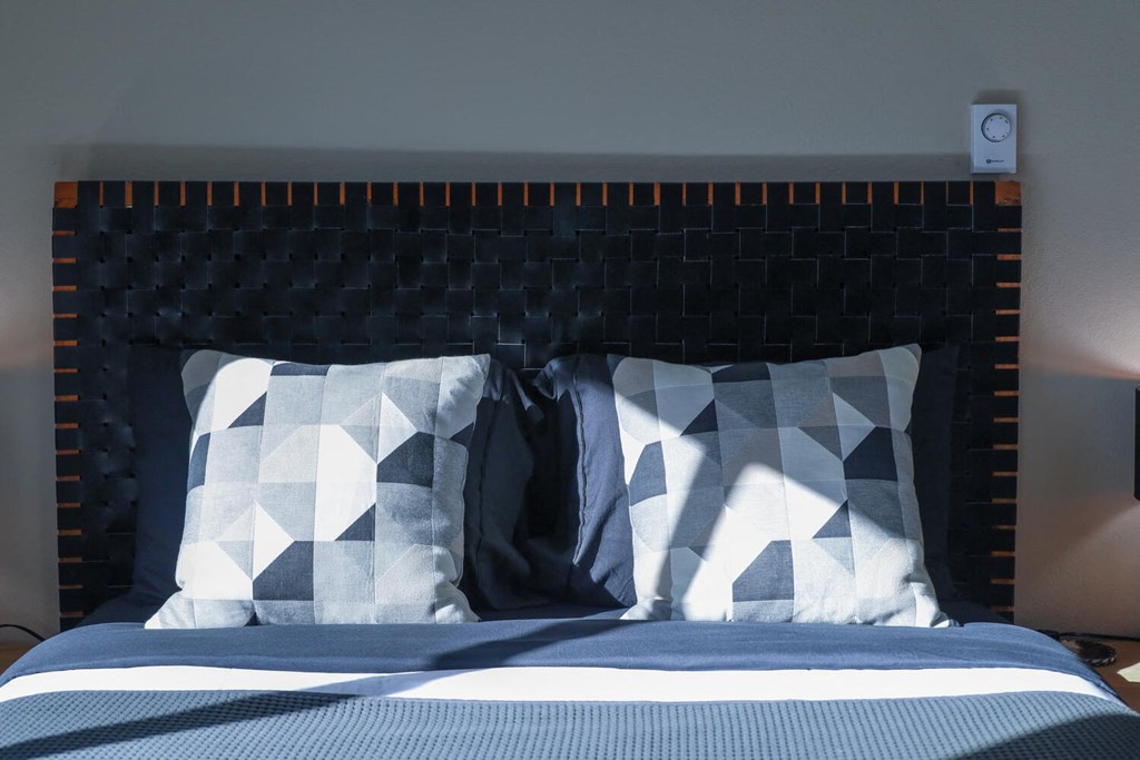 a bed with blue and white pillows and a black headboard