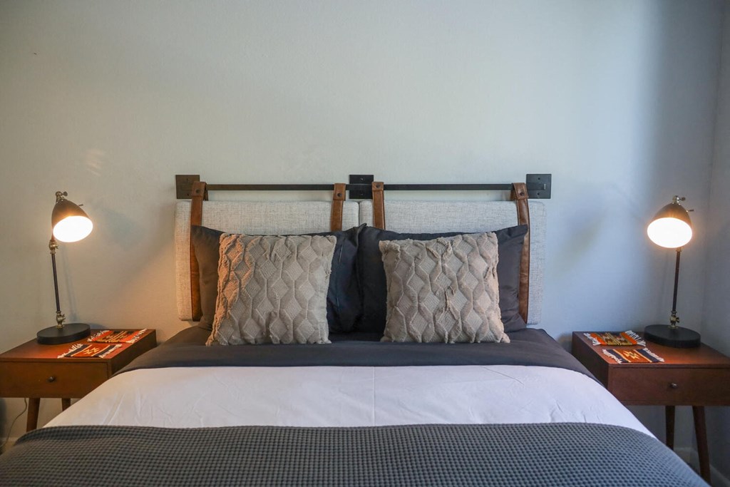 a bedroom with a bed with pillows and two lamps