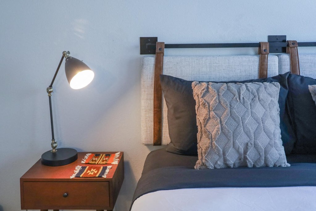 a bedroom with a bed and a nightstand with a lamp